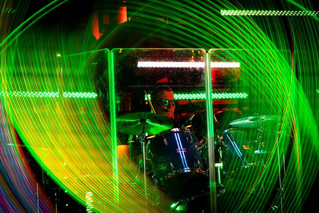 Drummer behind the kit, surrounded by green laser light