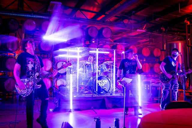 Random Riot playing a full set on stage, the whole five-piece lineup under purple and blue lights