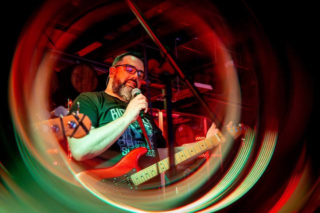 Guitarist singing into the mic under deep red lighting