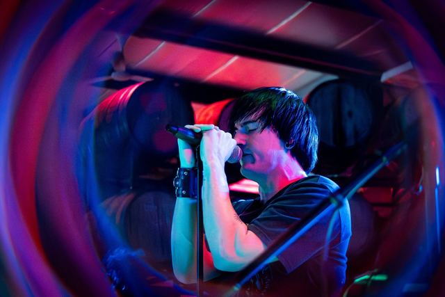Random Riot's singer at the mic under blue and magenta stage lights