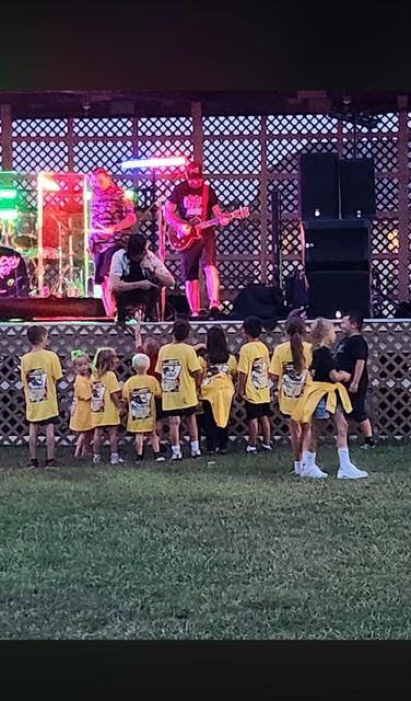 A row of young race fans in team shirts watching Random Riot play at Mole Lake Casino