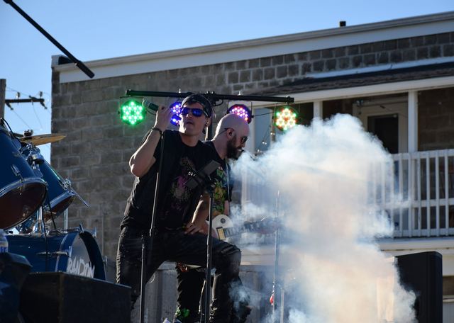 Two of the band on an outdoor stage with smoke rolling across it